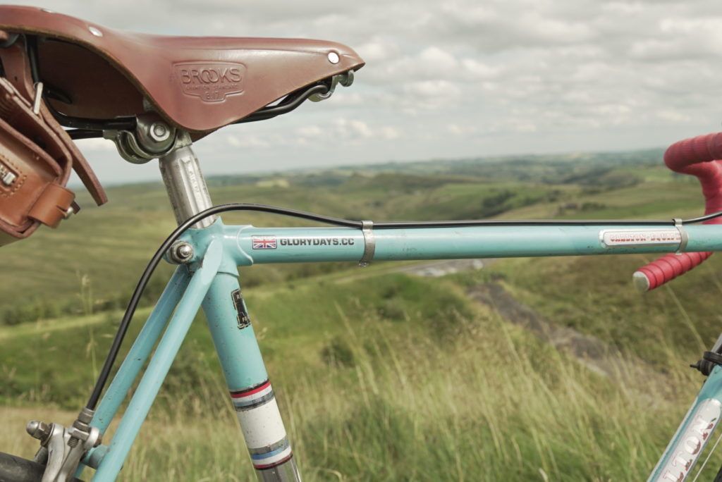 Close up of a Glory Days Bike vintage bike (leather saddle and duck egg blue cross bars) with the Peak District scenery in the background